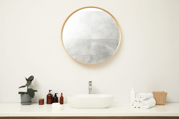 Countertop with sink, towels, houseplant and mirror in bathroom