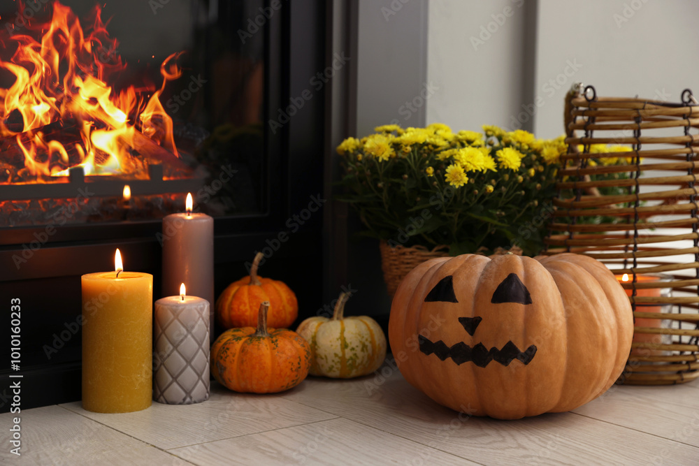 Poster Pumpkins, burning candles and flowers near fireplace indoors. Halloween celebration