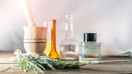 Bottle glass of essential Rosemary oil with fresh rosemary leaves, herbal oil concept