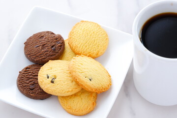 白いお皿に盛ったおいしそうなクッキーと、淹れたての香ばしいコーヒーで、コーヒーブレイクの幸せな時間
