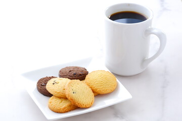 白いお皿に盛ったおいしそうなクッキーと、淹れたての香ばしいコーヒーで、コーヒーブレイクの幸せな時間
