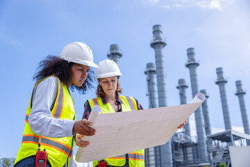 Female Engineers Reviewing Blueprints at a Power Plant Construction Site in Bright Daylight