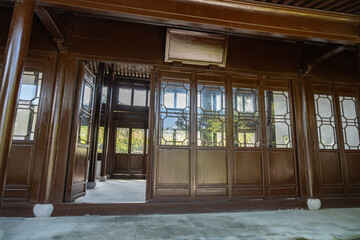 Entrance at the front porch to a new replica historic traditional Chinese pavilion or house, featuring a wooden door, walls, lattice windows, and a tiled floor