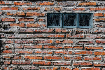 A textured brick wall with gray mortar and three decorative glass blocks, blending rustic and modern elements, perfect for architectural or background use