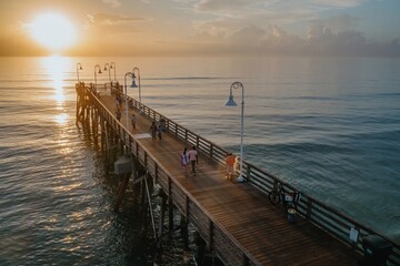 Fototapeta premium People fishing off the Daytona Beach Main Street Pier and calm ocean at sunrise, Daytona Beach, Florida, United States.