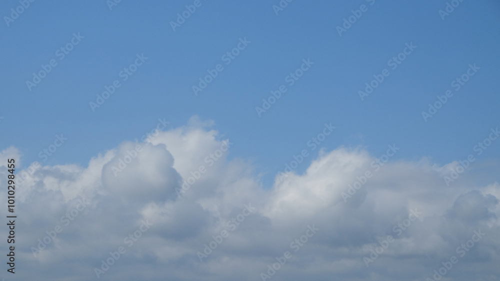 Poster blue sky with dramatic white clouds in abstract shapes, patterns and textures. clumpy clouds in the 