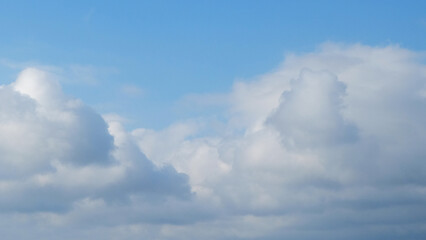 Blue sky with dramatic white clouds in abstract shapes, patterns and textures. Clumpy clouds in the blue sky. For graphic design or banner background