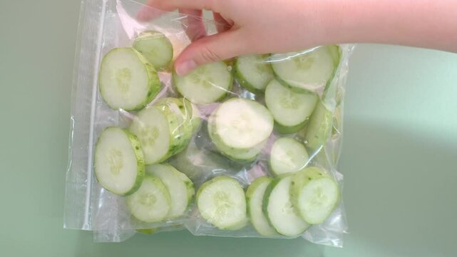 Cut vegetables and fruits in cellophane bags on a green background close-up top view.