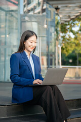 Working woman concept a female manager attending video conference and holding tablet, smartphone on street