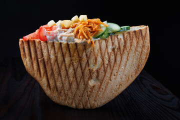Doner with a crispy crust and delicious meat and vegetable filling on a dark background.