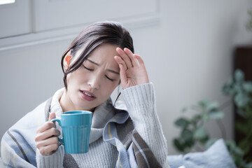 Close-up of a woman who is sick and unwell at home with a cold, fever headache or migraine 