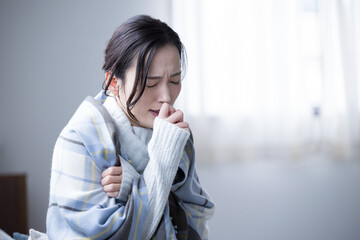 自宅で風邪や発熱で喉の痛み、体調不良で具合の悪い、咳込む女性