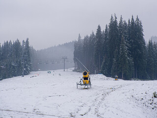 Snow guns (snow generator) on a ski track, machine gun, snow cannon for the production of artificial snow in the mountains. Ski road in Bukovel ski resort, Ukraine on the ski season.