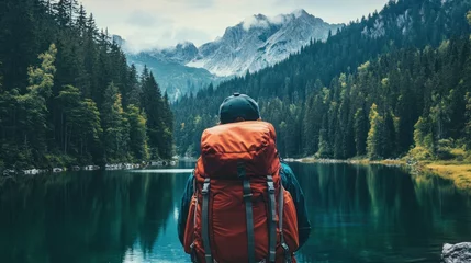 A lone hiker with a backpack admires the view of a lake and mountains © Faizatun