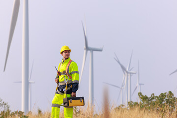 engineers wearing uniform and hardhats standing at wind turbines farm.
