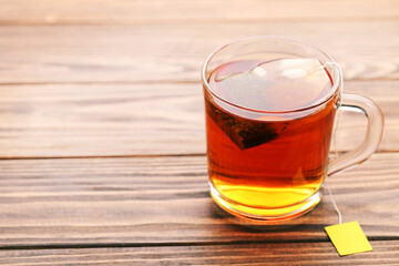 Cup of tea with tea bag on brown wooden table