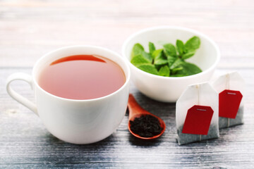 Cup of tea with mint leafs and spoon on wooden table