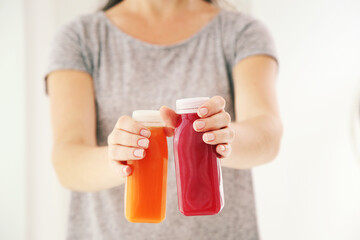 Woman holding in hands plastic bottles with red and orange smoothie