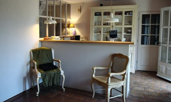 Int&eacute;rieur d&rsquo;un mas proven&ccedil;al en France, vue sur l&rsquo;entr&eacute;e depuis le jardin, cuisine semi-ouverte dite "cuisine am&eacute;ricaine" donnant sur la salle &agrave; manger