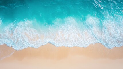 An aerial view of a sandy beach and turquoise ocean waves crashing on the shore.