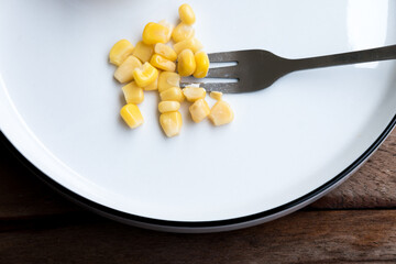 Cooked corn kernel, a small portion on the plate, a concept photo for a diet