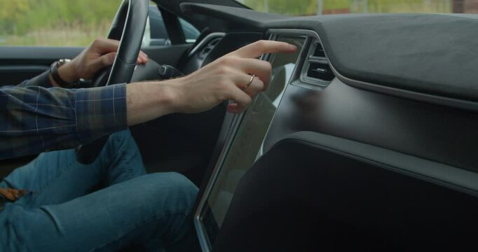 Male hand switches modes on control panel in electric car.