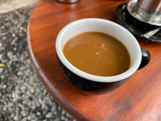 coffee with milk in a black glass, served on the table