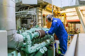 Naklejka premium Marine Engineer in blue overall working in Engine room of ship. Work at sea. Motorman.