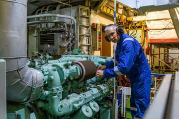 Marine Engineer in blue overall working in Engine room of ship. Work at sea. Motorman.