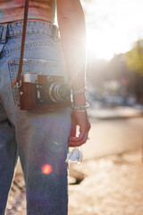 young girl in stylish clothes walks around the city and takes photographs with a film camera.