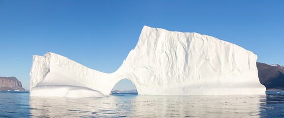 Large glaciers in the Atlantic Ocean, a glacier in West Greenland. Blue sea and blue sky at sunset. Melting glaciers off the coast of Greenland.  Aerial view.