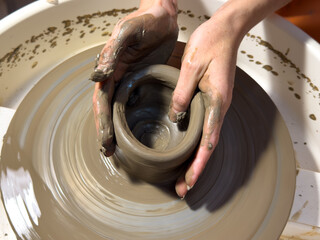 A person is making a pottery piece in a pottery wheel