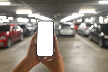 Hand holding a smartphone with a blank white screen in an underground parking garage