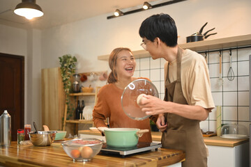 Young couple enjoying a lighthearted moment while preparing a meal together in kitchen