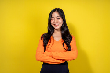 Obraz premium A woman in an orange shirt is smiling and standing in front of a yellow wall