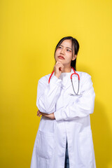 A woman in a white lab coat is standing in front of a yellow background