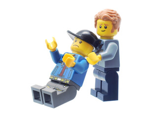 Naklejka premium Lego minifigure helps an injured man with tear drop on the faxe. Editorial illustrative image of popular plastic toys.