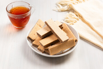 Chocolate flavored wafers on a white plate with a cup of tea in the background. with copy space. perfect for recipe, article, catalogue, or any commercial purposes.