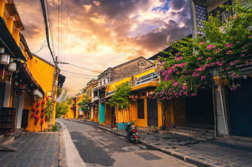 Streets with traditional ancient yellow houses in the old town in Hoi An city in Vietnam in summer at sunset