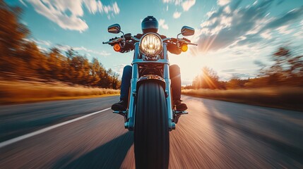 A low angle dynamic shot of a biker riding a motorcycle at high speed on an open road