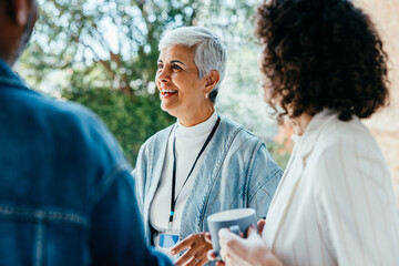 Mature female professional enjoying a casual conversation outdoors with colleagues