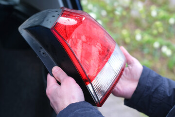 car rear lights, close-up male hands install red and white rear view advanced head-lights on black...