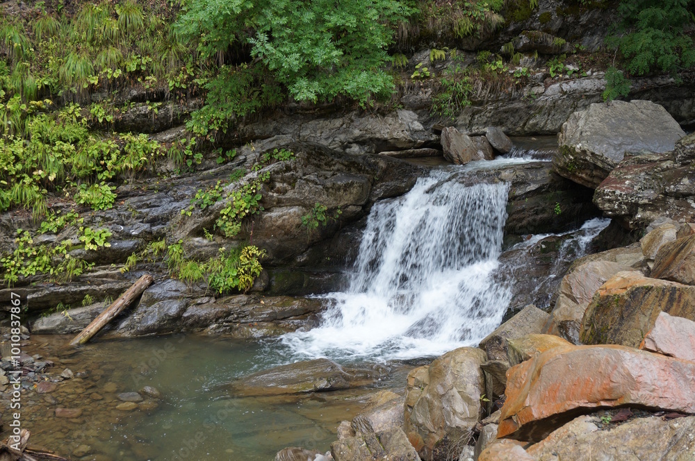 Poster A beautiful waterfall in a mountainous and wooded area. Mendelikha Park.