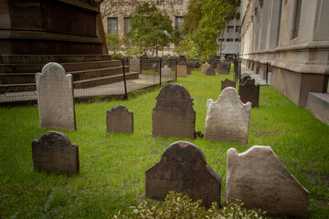 Antiguas lápidas en el cementerio junto a Trinity Church en el 89 de Broadway. Cementerio rodeado de los rascacielos del distrito financiero del Bajo Manhattan, Nueva York, EE. UU. Noviembre, 2019.