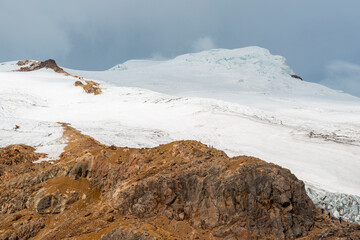 Cayambe volcano peak glacier with people silhouettes hiking the descent at high altitude, Andes Mountains, Ecuador.