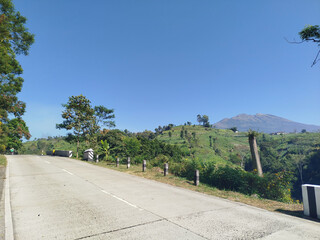 road with mountain background. rural road in mountain area with many trees which is cool and fresh