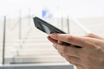 Woman's hands holding smartphone and using a social media at night street.