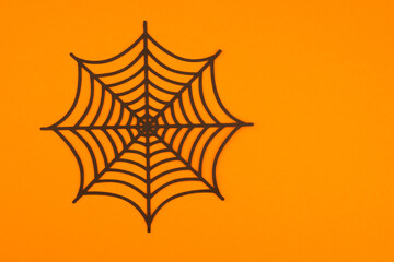 Black spider web against a bright orange background for Halloween decorations