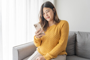 Pregnant asian woman holding smartphone at home using mobile app for pregnant women