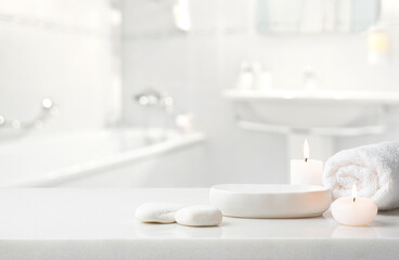 Stones, burning candles, towel and ceramic stand for spa product display on blur bathroom background